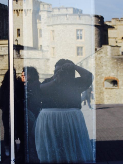 Girl holding camera takes picture in reflection, castle in background